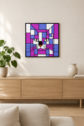 A framed square wall art print featuring a stylized cat face made of geometric blocks in purple, blue, pink, white, and black, hanging above a light wood console in a modern living room with a plant and vase.
