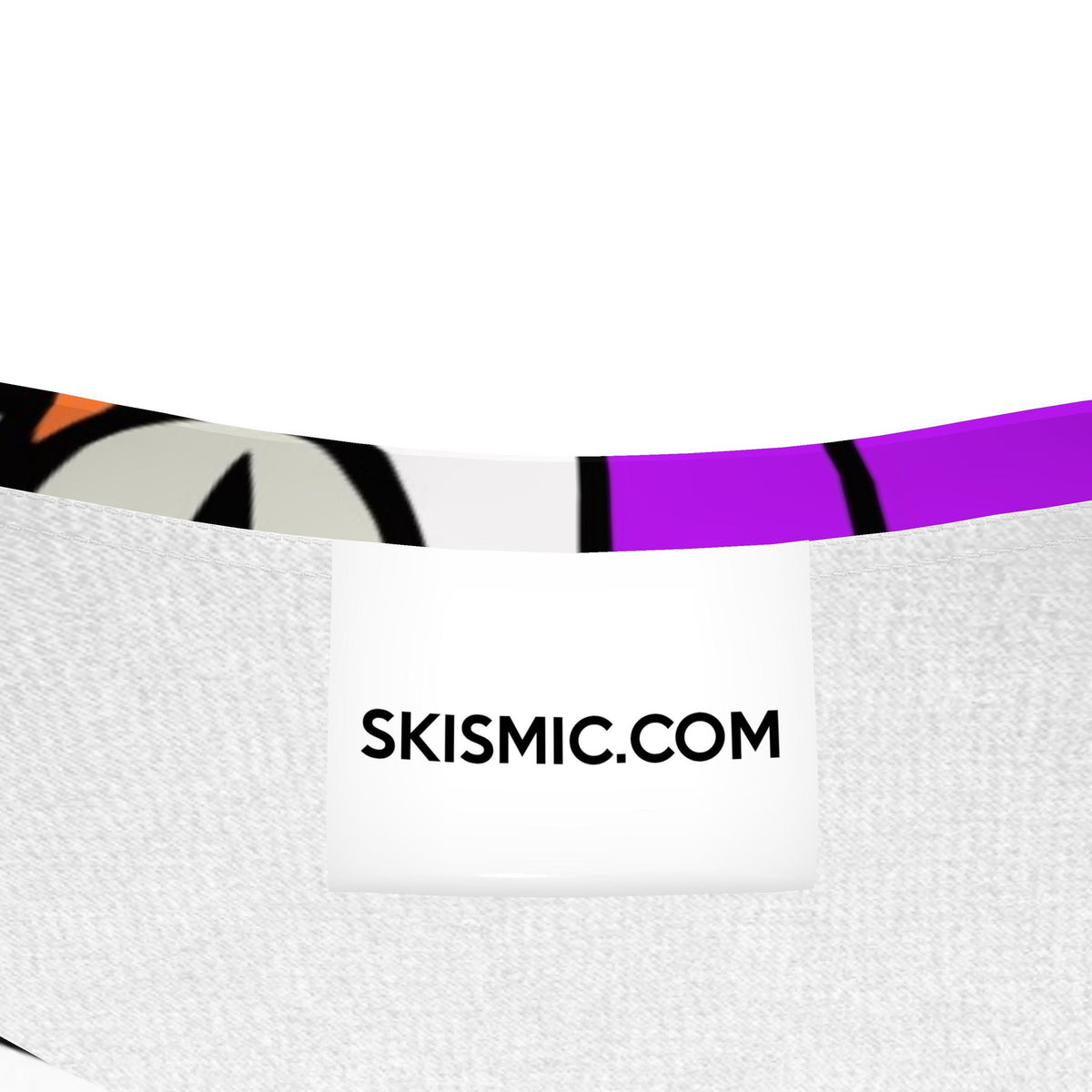 Close-up of the inside waistband of a pair of shorts, showing a white fabric waistband with a colorful abstract pattern in purple, black, orange, and gray. A white paper label in the center reads 'SKISMIC.