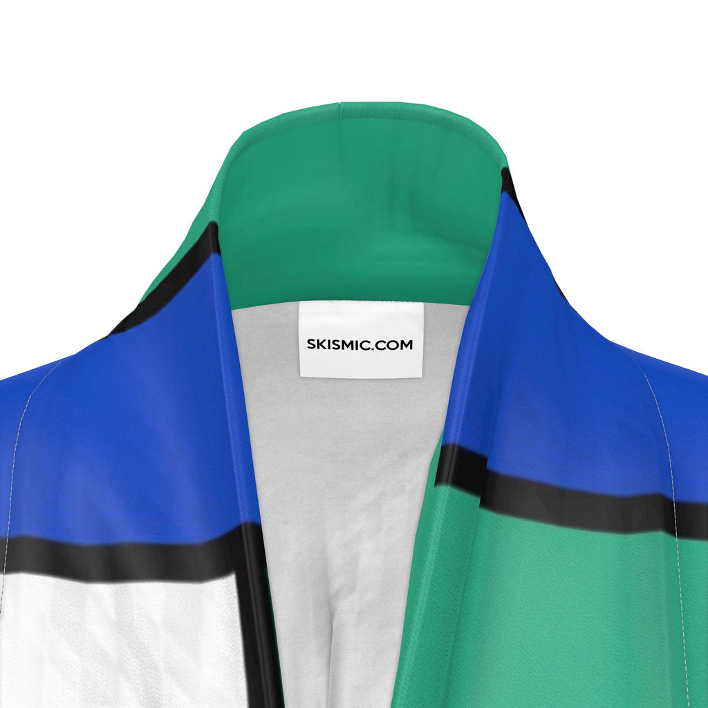 Close-up of a color-blocked kimono with green, blue, white, and black panels, featuring a white neck label that reads 'SKISMIC.COM'.
